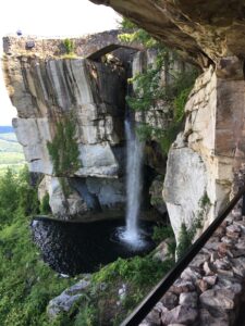Breathtaking view of Lover’s Leap at Lookout Mountain, featuring a cascading waterfall from a high cliff into a serene pool below, with a scenic bridge and overlook above the falls.