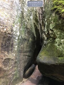 Tight crevice between mossy boulders at Lookout Mountain labeled “Needle’s Eye,” forming a dramatic natural corridor that hikers must carefully pass through.